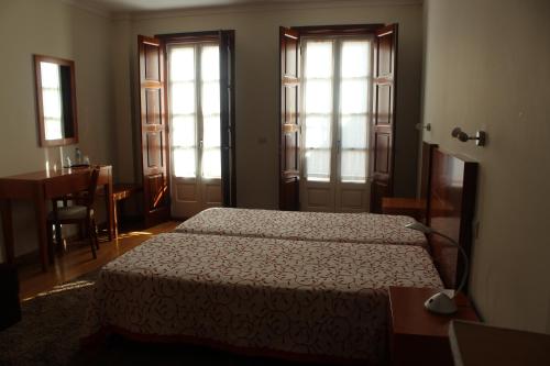 蒙考穆拉拉斯杜米诺旅馆的一间卧室设有两张床、一张桌子和窗户。