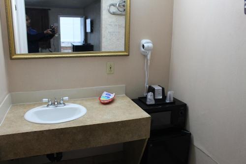 加洛韦大西洋城经济旅馆和套房的一间带水槽和镜子的浴室以及一部电话