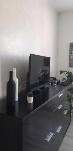 贝尔福COSY F3 PROCHE CENTRE的一张黑色的桌子,里面配有电视和电脑