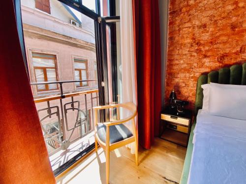 伊斯坦布尔RUZ Hotels Galata的一间卧室设有一张床、一个窗口和一把椅子
