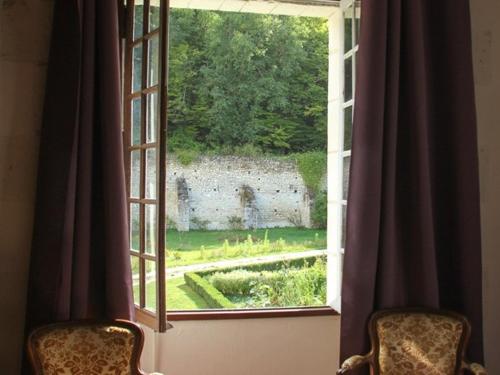 蒙特雷索Chateau-monastère de La Corroirie的窗户配有两把椅子,俯瞰着花园