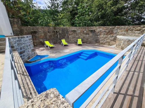 特拉什杜博鲁Quinta do Avô - Casa de Campo的一个带石墙和两张黄色椅子的游泳池