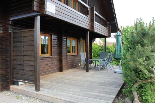 LoissinHolzblockhaus mit Kamin am Kite , Surf und Badestrand的房屋设有木甲板,配有桌椅