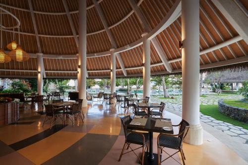 纳闽巴霍Sudamala Resort, Komodo, Labuan Bajo的一间带桌椅和大型天花板的餐厅