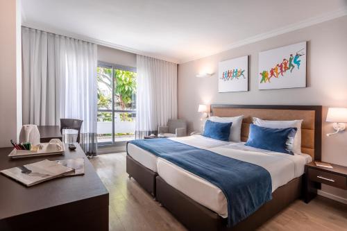 拉马特甘Kfar Maccabiah Business & Sport Hotel的酒店客房设有一张大床和一张书桌。
