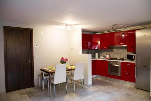 奥斯塔Maison Poppy的厨房配有红色橱柜和一张带白色椅子的桌子