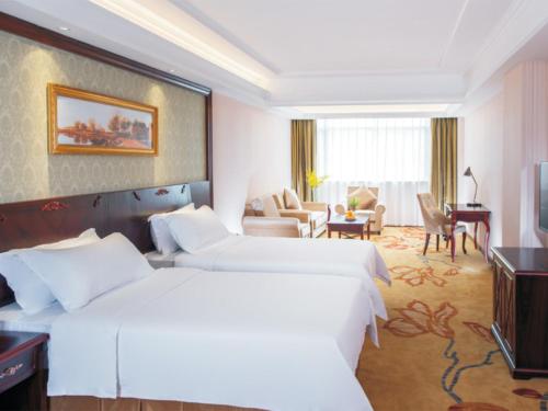 宝安维也纳酒店深圳石岩石龙社区店的酒店客房带两张床和一个客厅