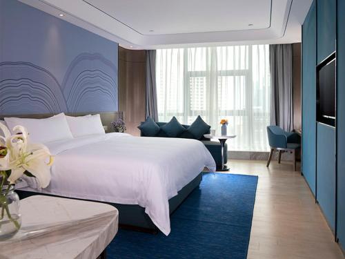 海口维也纳酒店 (海口国际会展中心店)的卧室配有一张白色大床和蓝色的墙壁