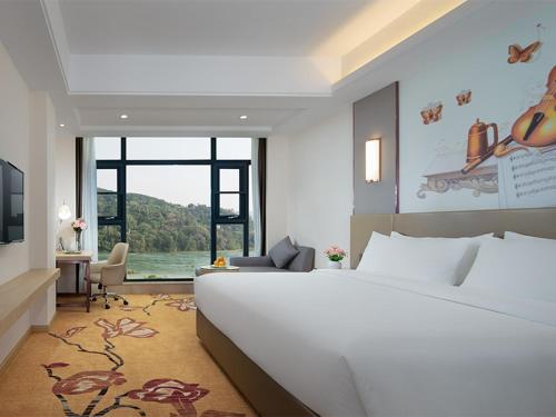 景洪市维也纳国际酒店 (云南西双版纳景洪告庄滨江俊园店)的卧室设有一张白色大床和大窗户