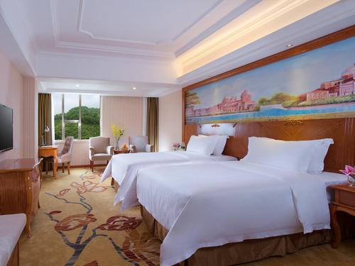 深圳维也纳国际酒店深圳草埔金稻田店的一间卧室设有两张床,墙上挂着一幅大画