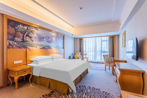 佛山维也纳酒店佛山罗村机场店的酒店客房设有一张大床和一张书桌。