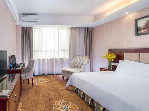 龙岗维也纳酒店深圳龙岗南联店的酒店客房带一张大床和一把椅子