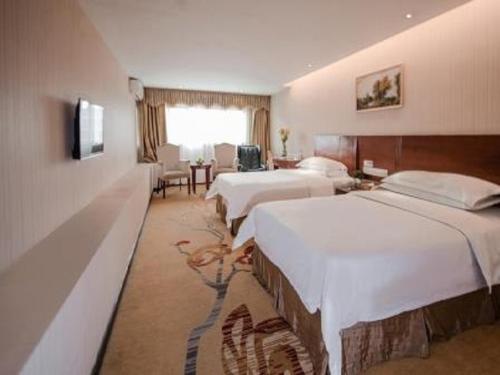 宝安维也纳3好店深圳观澜高尔夫店的酒店客房带两张床和一张桌子以及椅子。