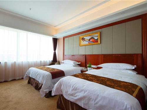 上海维也纳国际酒店上海浦东机场华夏东路地铁站店的酒店客房设有三张床和窗户。
