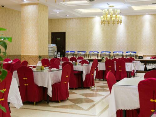 松江维也纳酒店(上海欢乐谷店)的一间带桌子和红色椅子的用餐室以及吊灯