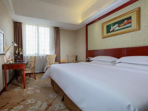 成都维也纳酒店成都会展中心店的酒店客房设有一张大床和一张书桌。