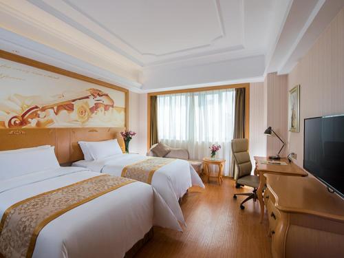 佛山维也纳国际酒店佛山南海大道桂城地铁站店的酒店客房设有两张床和一台平面电视。