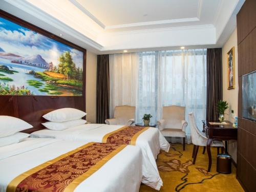杭州维也纳国际酒店 (杭州下沙大学城店)的酒店客房设有两张床,墙上挂有绘画作品