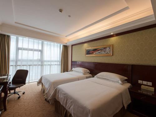 上海维也纳酒店上海虹桥机场中心店的酒店客房设有两张床、一张书桌和一个窗户。