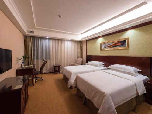 上海维也纳酒店上海虹桥机场中心店的酒店客房设有两张床和电视。