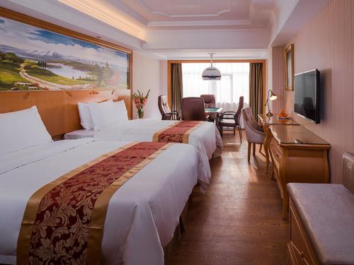 Fenghuangwei维也纳国际酒店 (深圳福永会展中心店)的酒店客房设有两张床、一张桌子和电视。