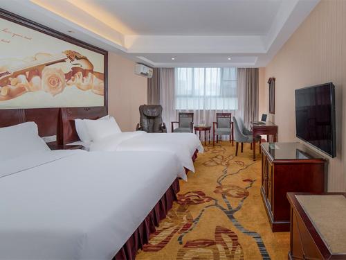 宝安维也纳酒店深圳沙井中心路店的酒店客房设有两张床和一台平面电视。
