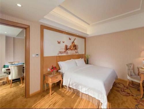 龙岗维也纳酒店深圳宝能城市广场店的卧室配有一张白色大床和一张书桌