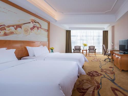 广州维也纳国际酒店广州长隆祈福新邨店的酒店客房配有两张床和一张书桌