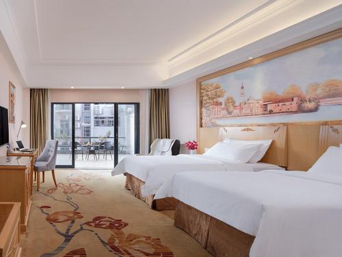 广州维也纳酒店广州番禺华南碧桂园店的酒店客房设有两张床,墙上挂着一幅大画。