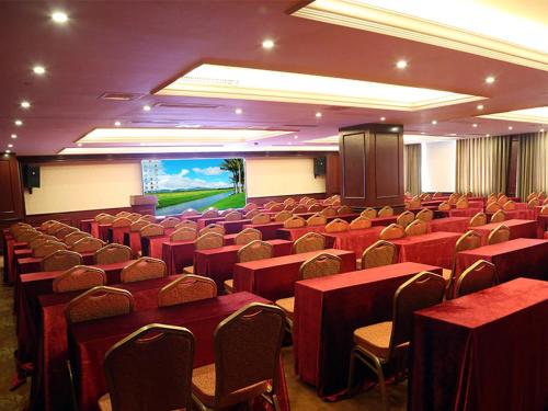 长沙维也纳国际酒店湖南长沙岳麓银杉路店的一间会议室,配有红色的桌椅和屏幕