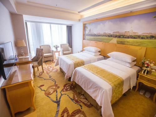 惠州维也纳酒店广东惠州江北三新店的酒店客房设有两张床,墙上挂有绘画作品