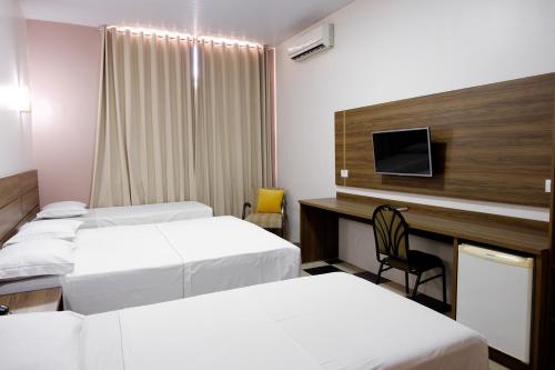 马拉巴Hotel del Príncipe的客房设有三张床和一张带电视的书桌。