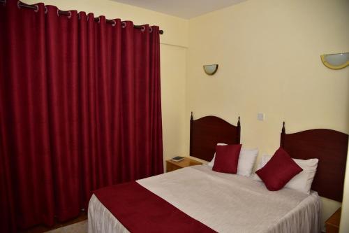 埃尔多雷特Klique Hotel Eldoret的一间卧室配有两张红色窗帘