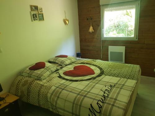 科尔尼蒙Appartement cosy calme à l'orée du bois的一间卧室配有一张带红色枕头的床和一扇窗户