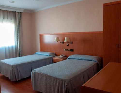阿特佛Hotel Lindaraja的酒店客房设有两张床和窗户。