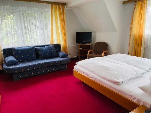 NeuhermsdorfLandhotel "Wettin"的一间卧室配有一张床、一张沙发和一台电视。