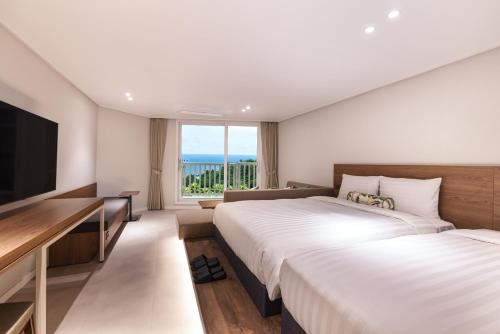 西归浦市Kensington Resort Jeju Jungmun的酒店客房设有两张床和一台平面电视。