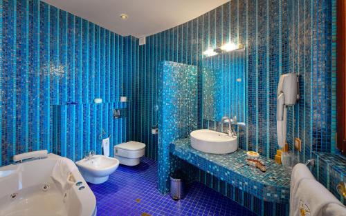 ElenovoHotel Soli Invicto的蓝色瓷砖浴室设有卫生间和水槽