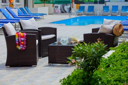 阿依纳帕Paloma Hotel Apartments的一组椅子和一张桌子,旁边是游泳池