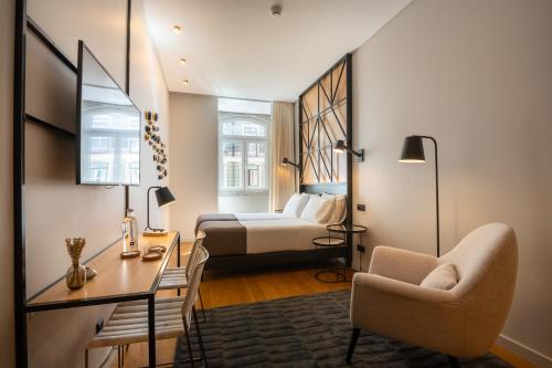 里斯本Ferraria XVI FLH Hotels Lisboa的一间卧室配有一张床、一张桌子和一把椅子
