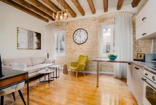 科孚镇Curcumelli Luxury Suites - ΚΟΡΚΥΡΑ的客厅配有沙发和砖墙上的时钟