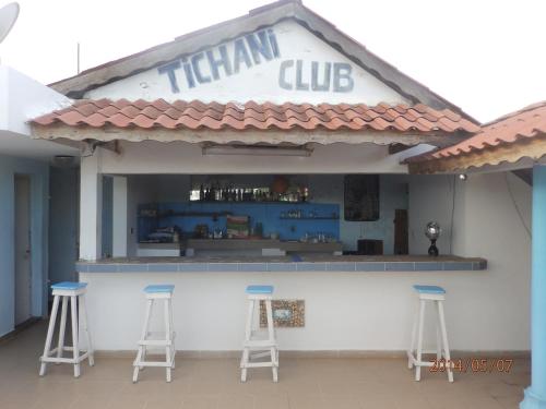科托努提查尼俱乐部住宿加早餐旅馆的治疗俱乐部,前面有三个酒吧凳子