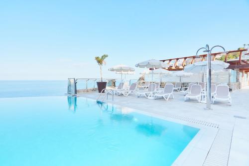 波多黎各凯莱宫阿马多雷斯塔拉索酒店的毗邻大海的带椅子和遮阳伞的游泳池