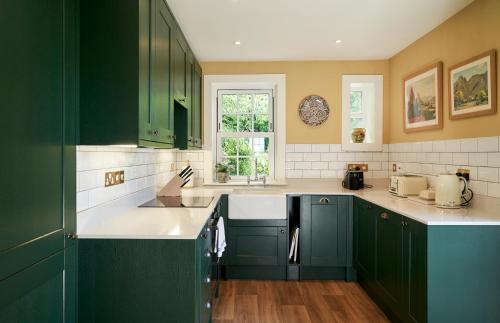 ColinsburghBalcarres East Lodge的厨房配有绿色橱柜和白色台面
