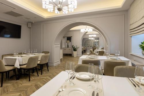 敖德萨Dvoryansky Hotel的餐厅配有白色的桌椅和吊灯