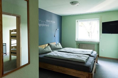 莱茵河畔的纳沙泰尔Hotel Check-Rhein - Self Check-in的一间卧室配有一张床、镜子和窗户