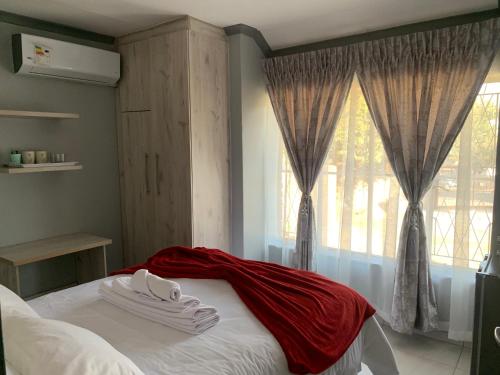 米德兰Waterfall View Lodge的一间卧室配有一张床铺,床上铺有红色毯子