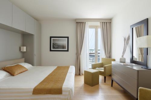 普林托迪斯卡利诺Marina di Scarlino Resort的一间卧室配有一张床、一台电视和一把椅子