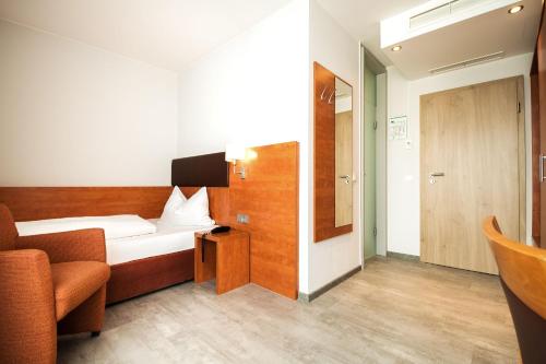 慕尼黑domus Hotel的小房间,配有一张床和一把椅子