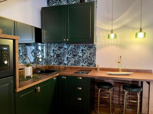 萨莫拉LA CASITA的厨房配有绿色橱柜和带凳子的台面